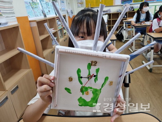 ▲ 중구 다운초등학교 학생이 기후위기대응 교육 수업에서 재활용품으로 만든 시계를 들어보이고 있다.
